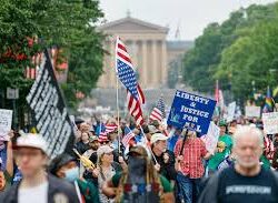 Crowd of people in a No Kings rally holding signs and flags against the backdrop of the Philadelphia Art Museum.