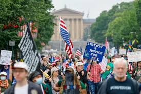 Crowd of people in a No Kings rally holding signs and flags against the backdrop of the Philadelphia Art Museum.
